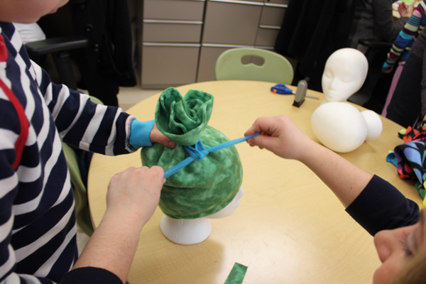 Bunch together the top of your hat and tie a piece of scrap fabric to form the separation between your hat and the pompom on top.