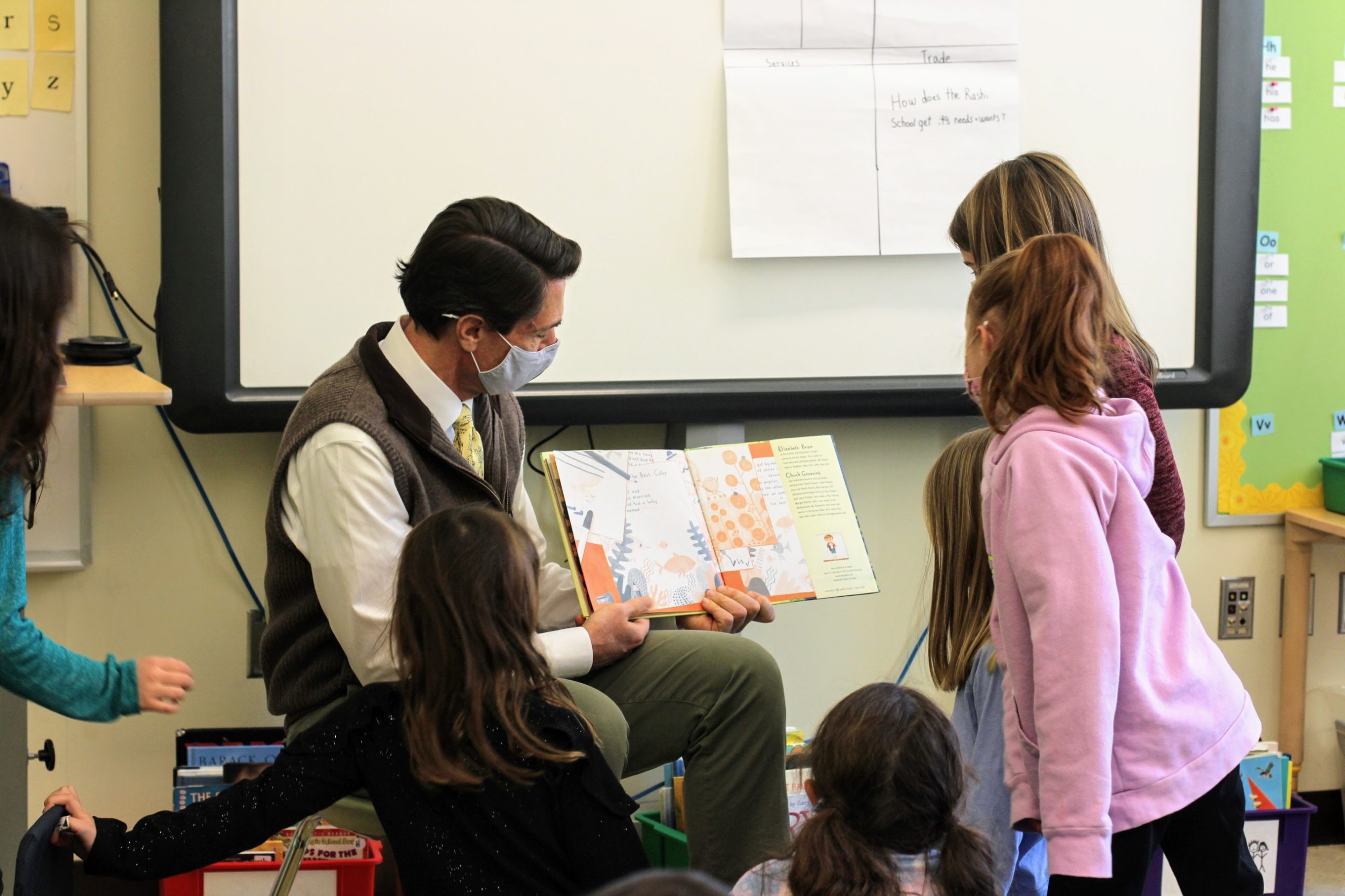 Grade 1 students gather around Adam Fischer to interact with the book he's reading