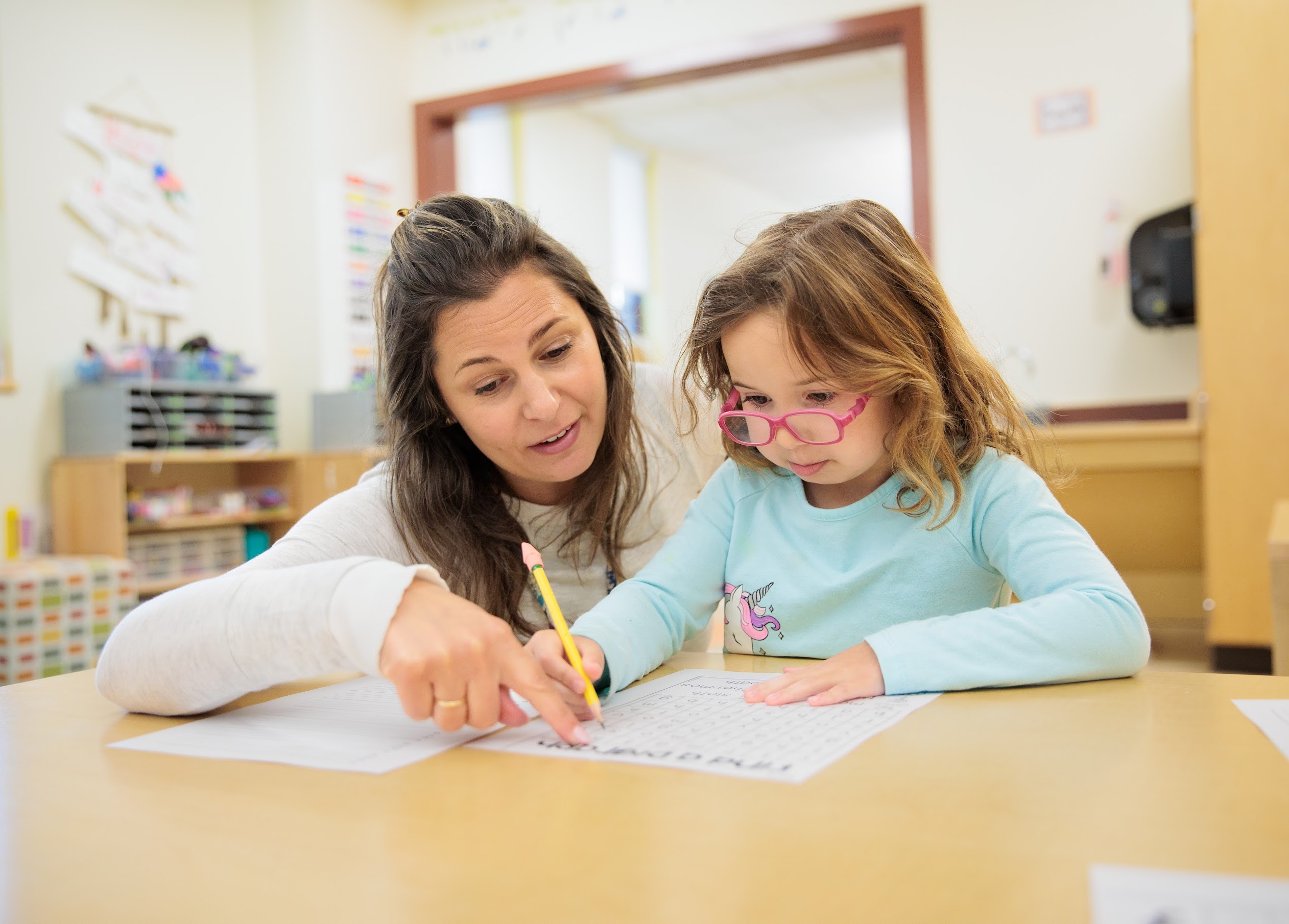 rashi_240502_287 A kindergarten teacher helps a student with a literacy worksheet