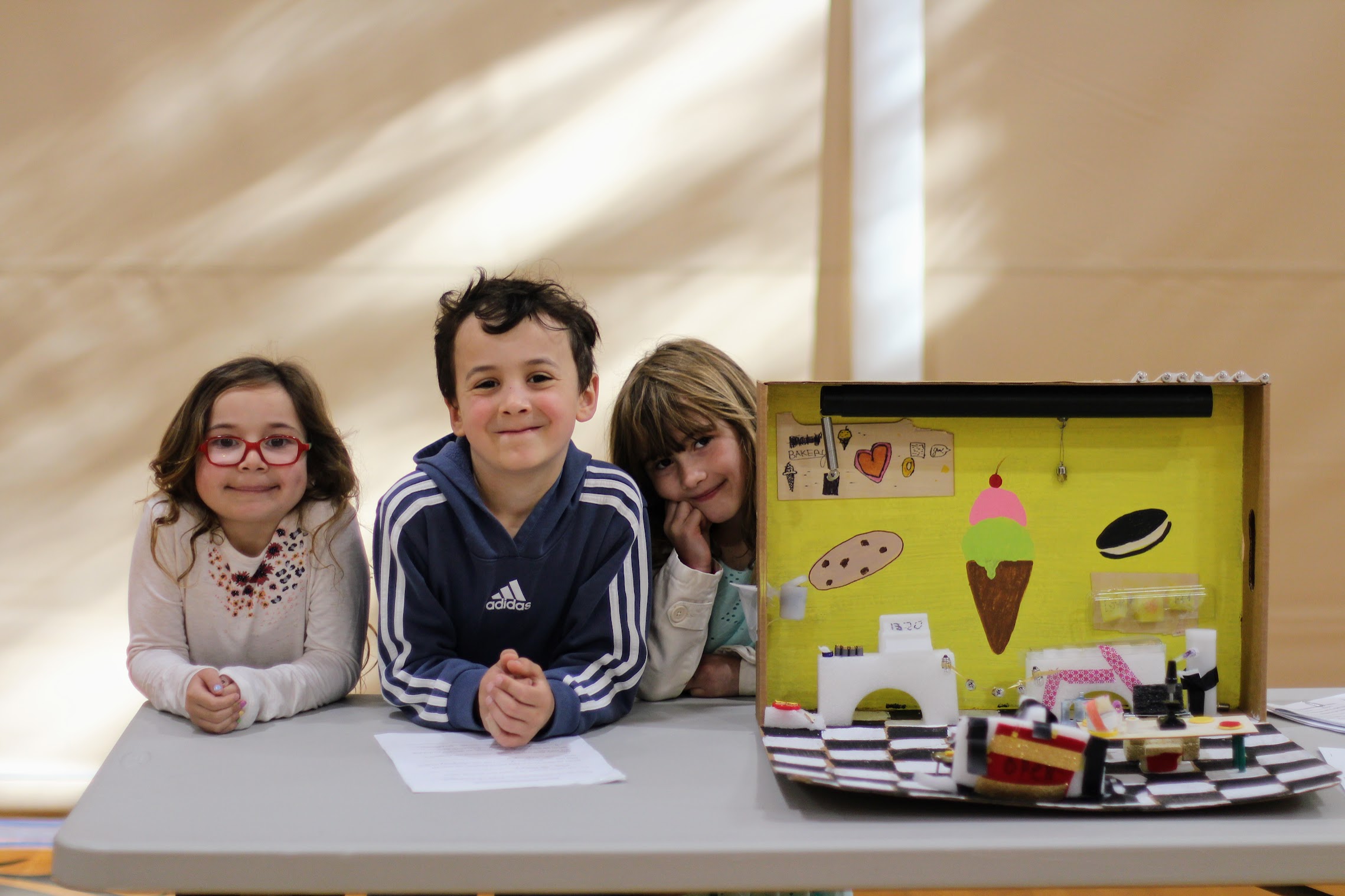 Three grade 1 students pose with their model