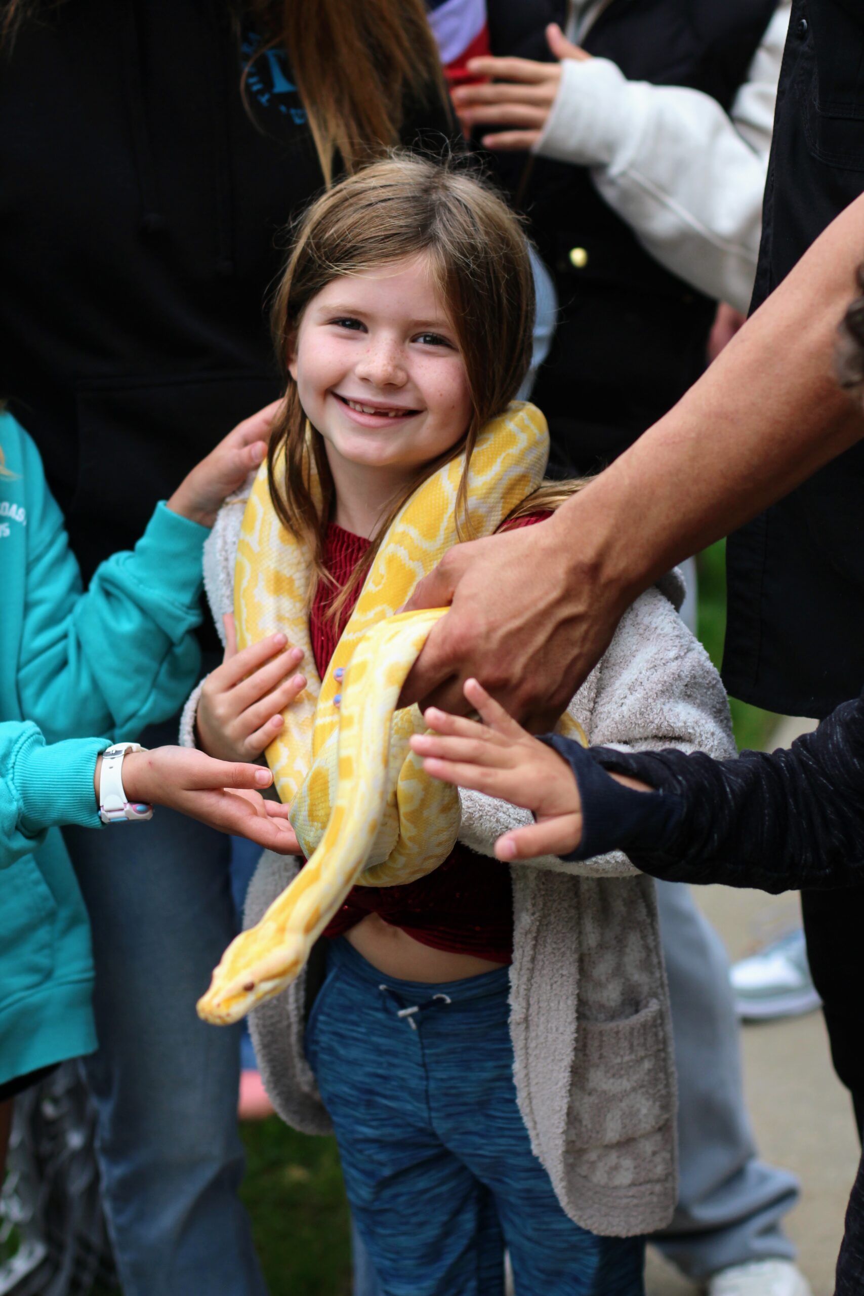 A girl holding a yellow snake around her neck