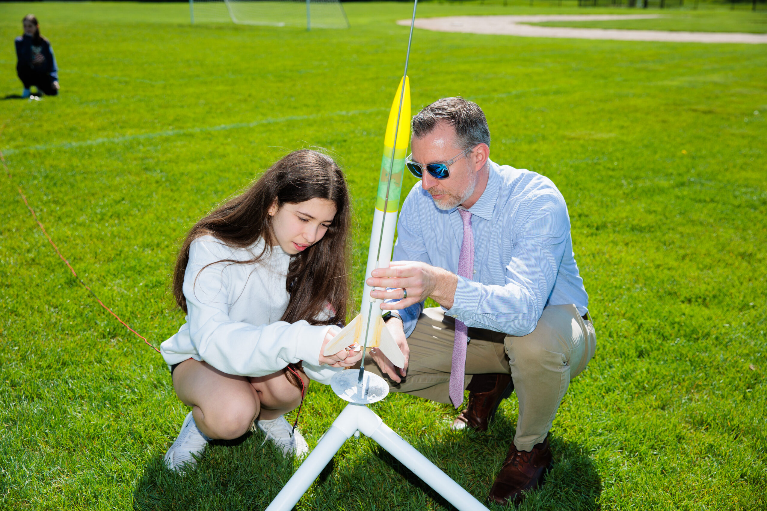 A girl holding a yellow snake around her neck